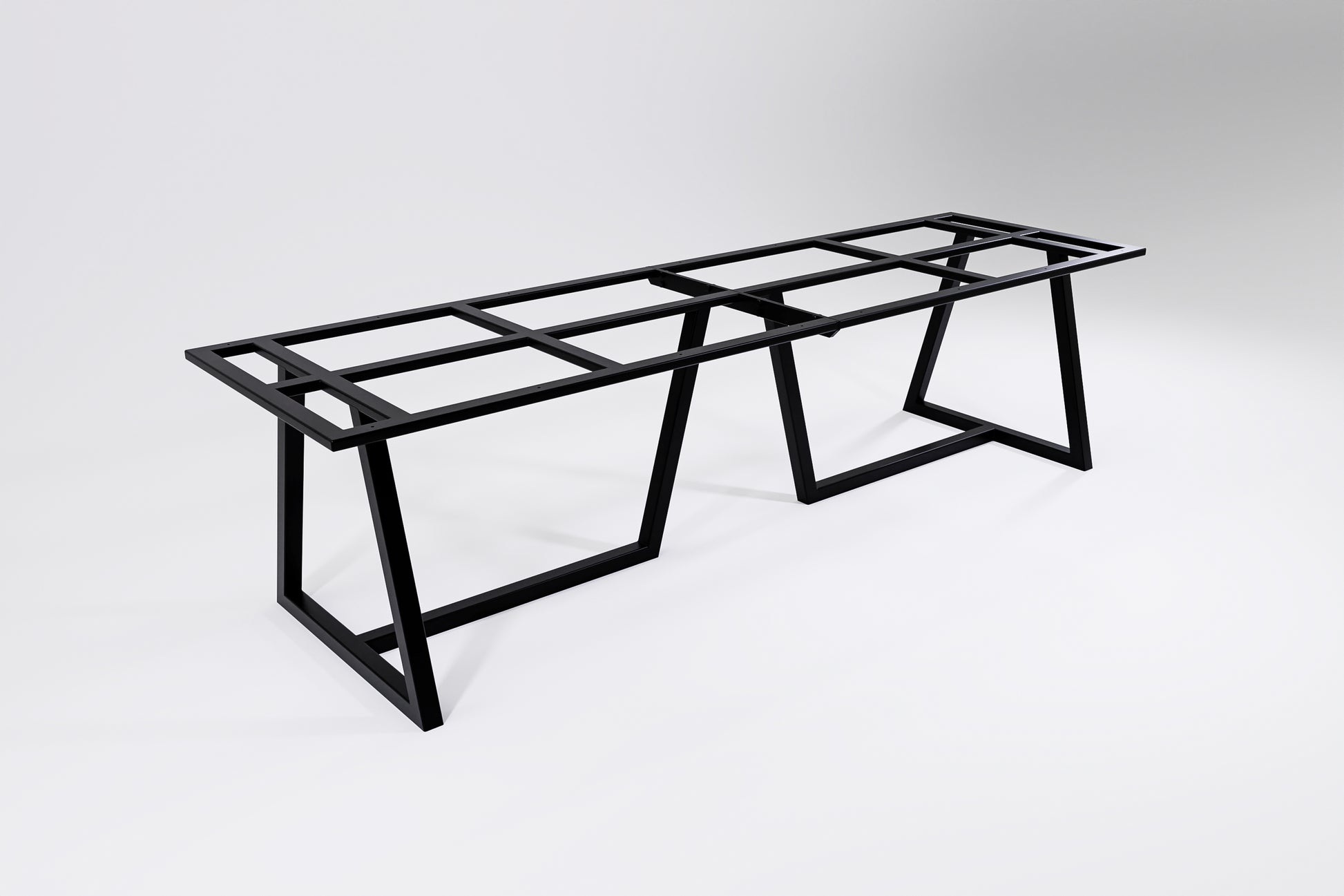 A black modular heavy-duty table base designed to be bolted together, consisting of two sections with table leg supports