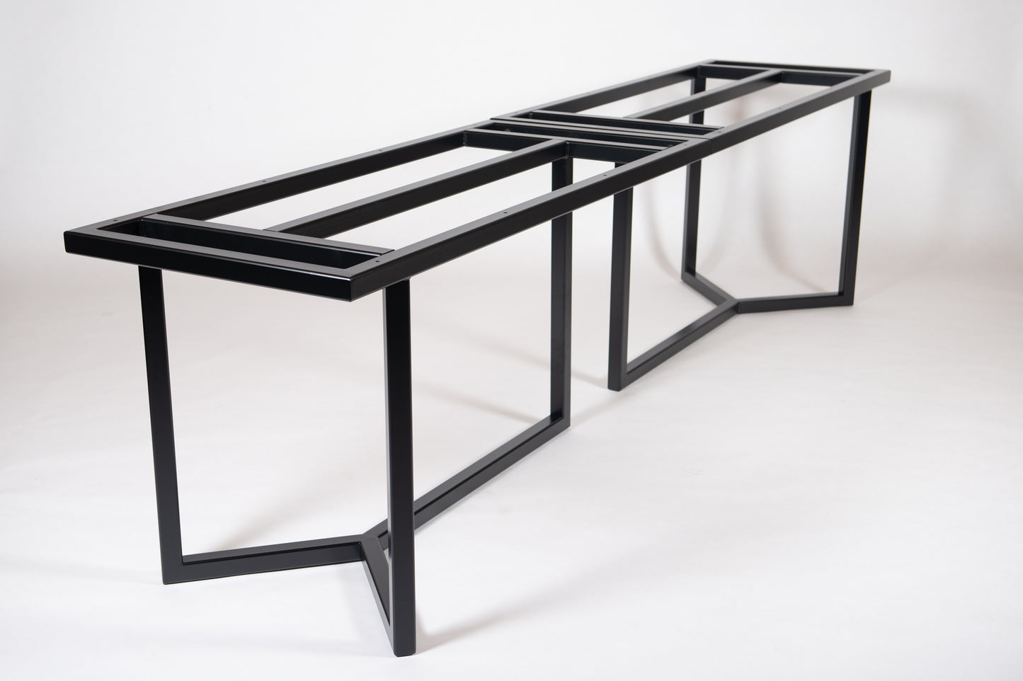 A heavy-duty black metal frame designed for forming large dining or conference tables.